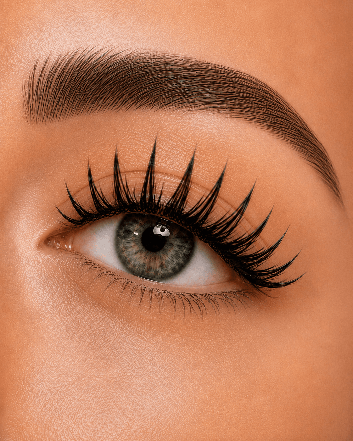 Close-up of a green eye with dramatic spiky eyelashes and a perfectly groomed dark eyebrow.