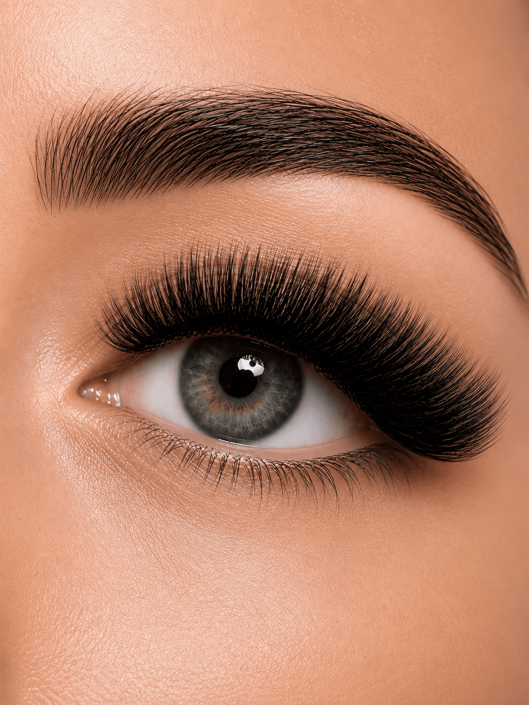 Close-up of a blue-green eye with voluminous black eyelash extensions and a groomed eyebrow.